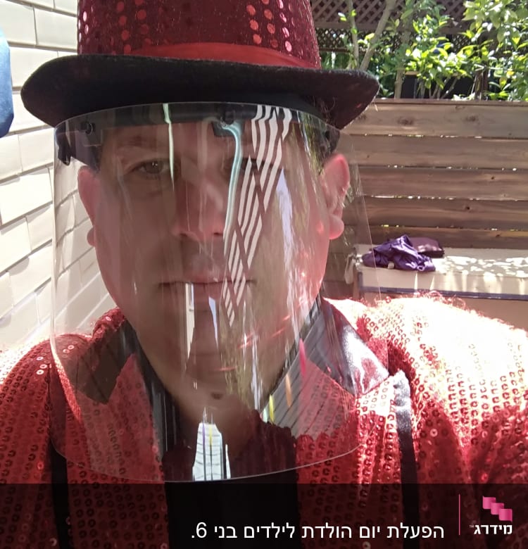 אדם בכובע אדום ונצנצים עם מסכת פנים